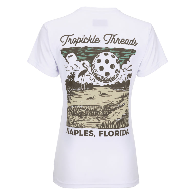 Introducing our latest creation: the Gator Women's Pickleball T-shirt. With its unique design featuring a gator under a full moon made of a giant Pickleball, this shirt adds Florida charm to your game. Crafted and printed in Naples, it blends style and performance seamlessly. Discover this exclusive addition to our collection of shirts, hats, and sportswear perfect for tournaments and everyday attire.